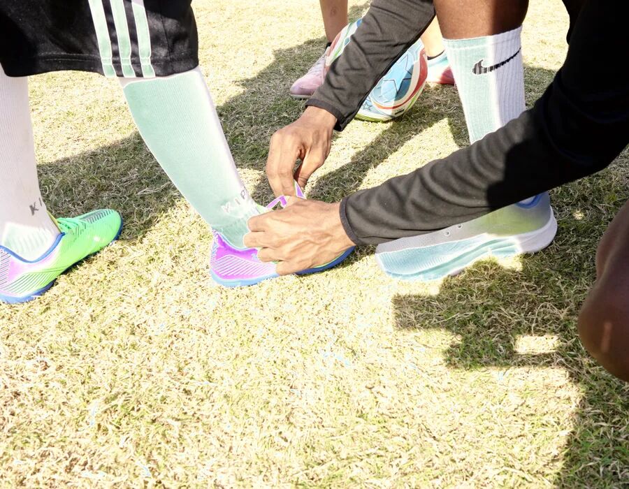 A coach fastening a young player's boots